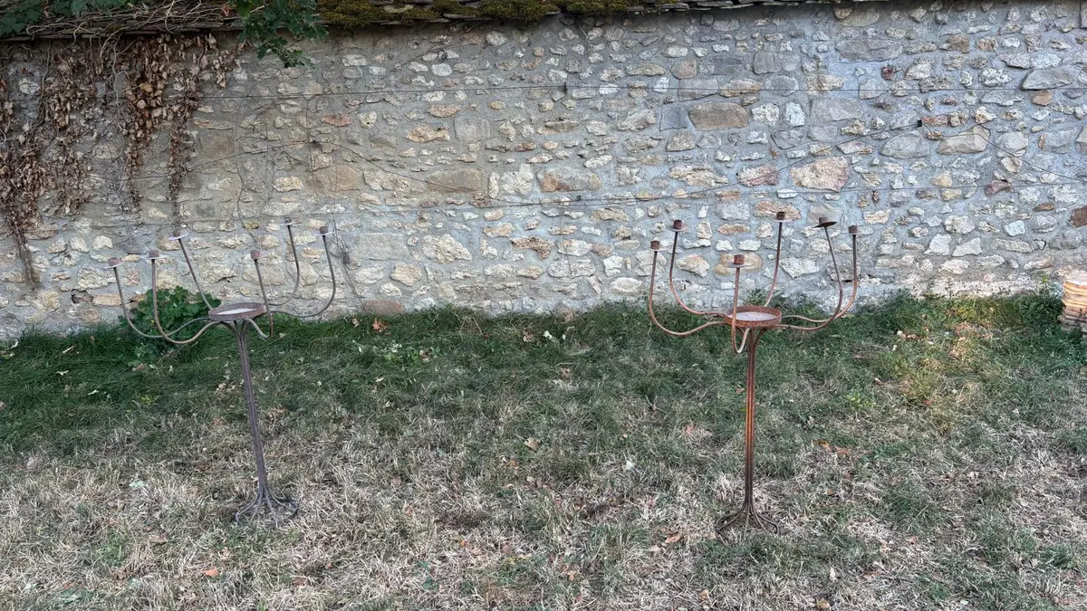 Paire de candélabres anciens en fer forgé, devant un mur de pierre