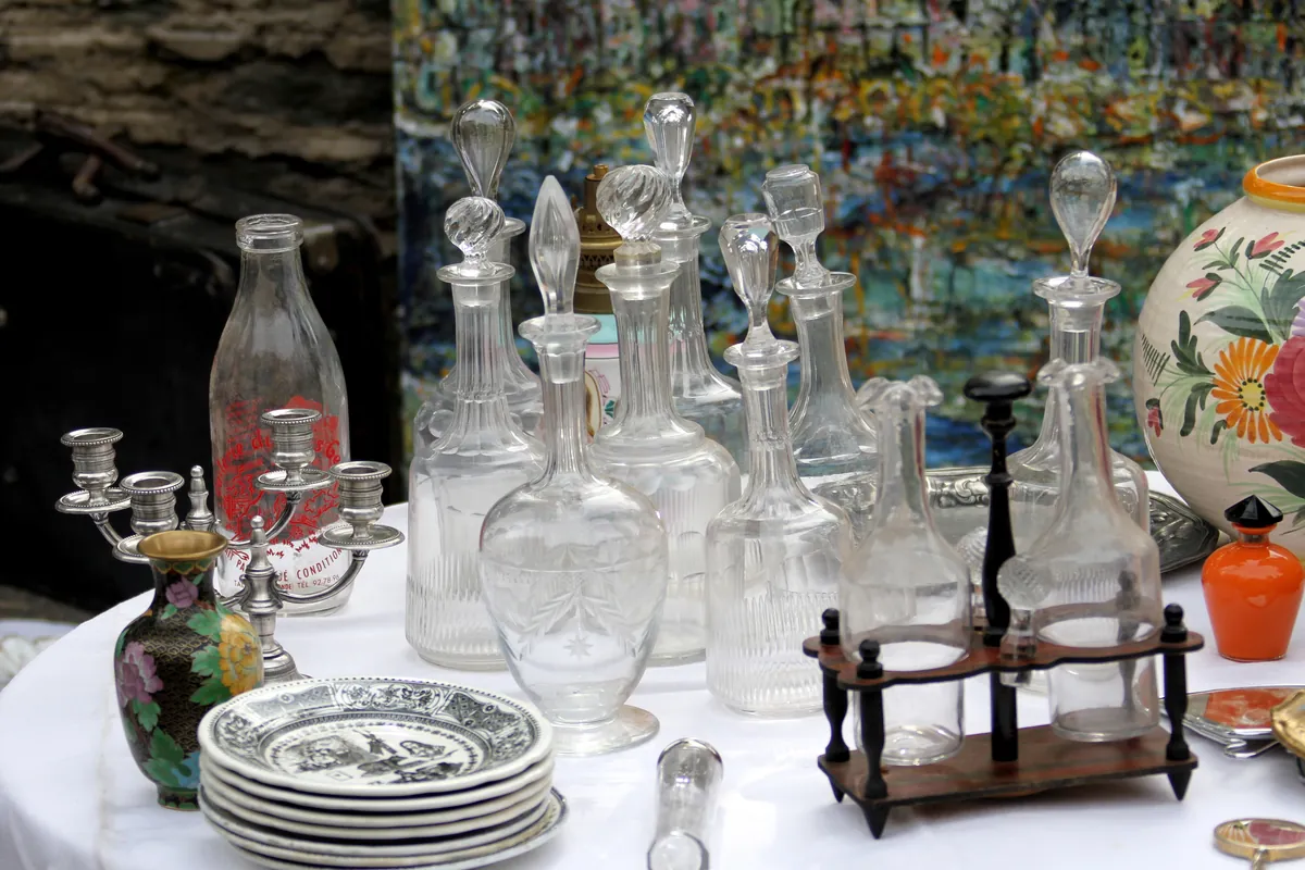 Carafes et flacons anciens en cristal, chandelier en étain et assiettes en faïence