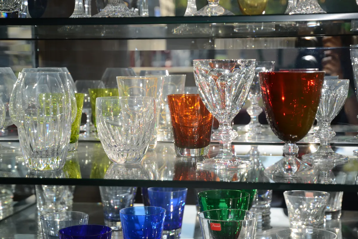 Verres en cristal taillé et verres de couleur de type Baccarat, alignés sur une étagère de vitrine